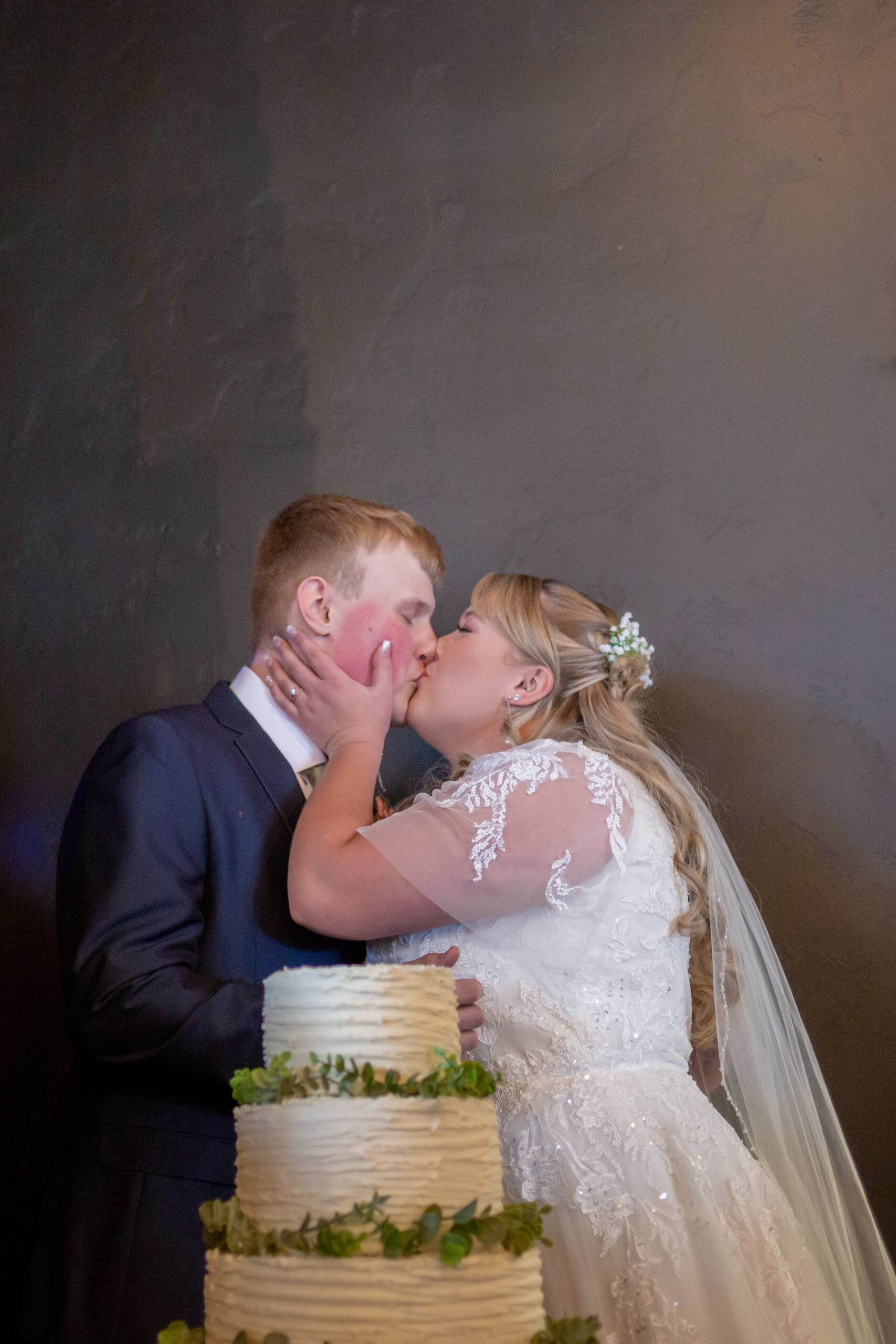 bride and groom kiss after cutting the cake