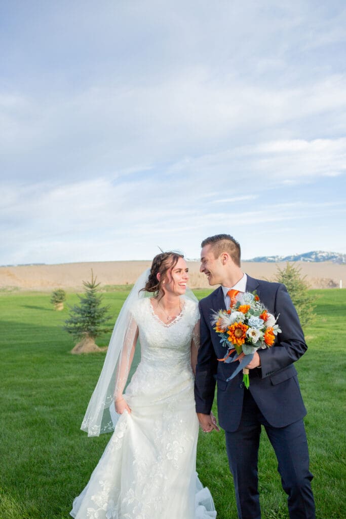 bride-and-groom-holding-hands-looking-at-each-other-walking
