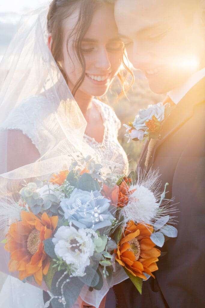 PNW Elopement Photographer captures bride and groom embracing while holding bouquet at sunset after they elope in PNW