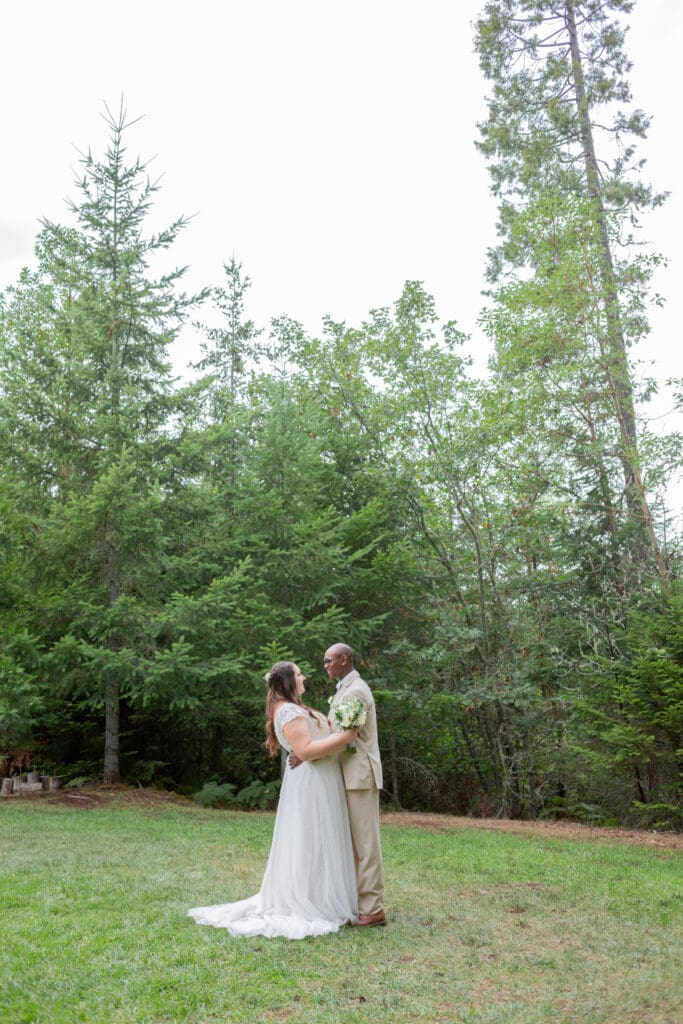Seattle Wedding Photographer captures inter-racial couple looking at each other in a grove of trees